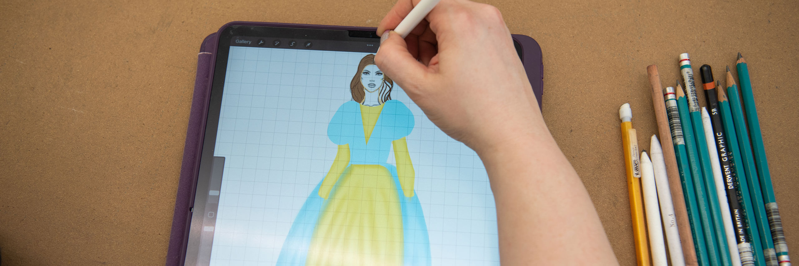 Graduate costume designer sketches a costume on her tablet.