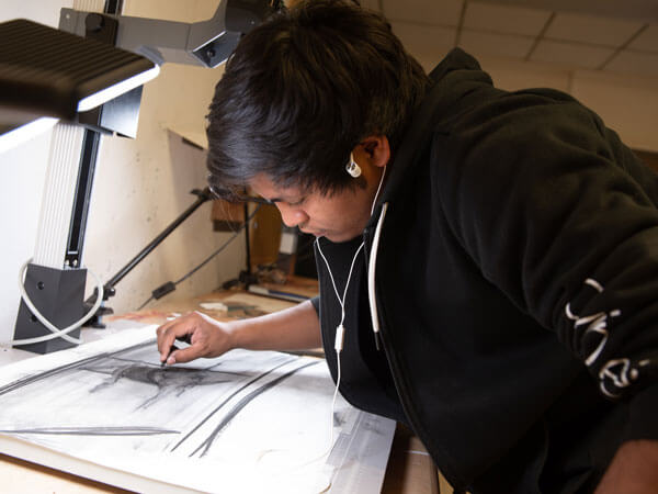 A drawing student draws with charcoal.