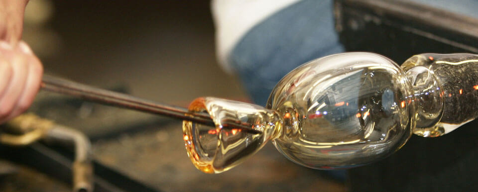 Student works on a glass-blown piece of art.