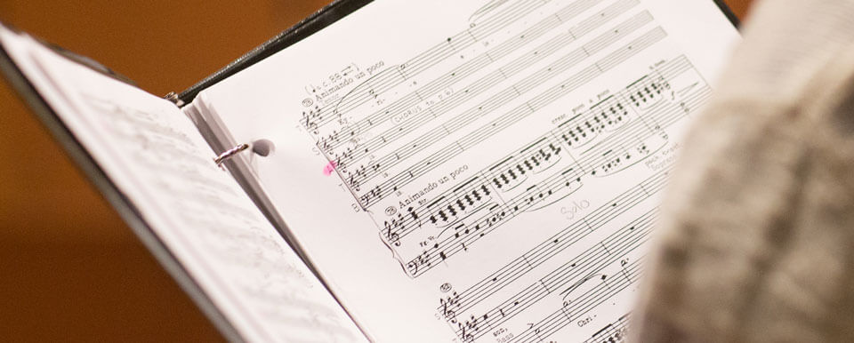 Sheet music in a binder being held by a vocalist.