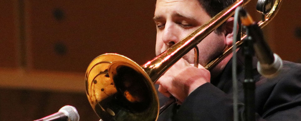 A trombonist plays into a microphone.