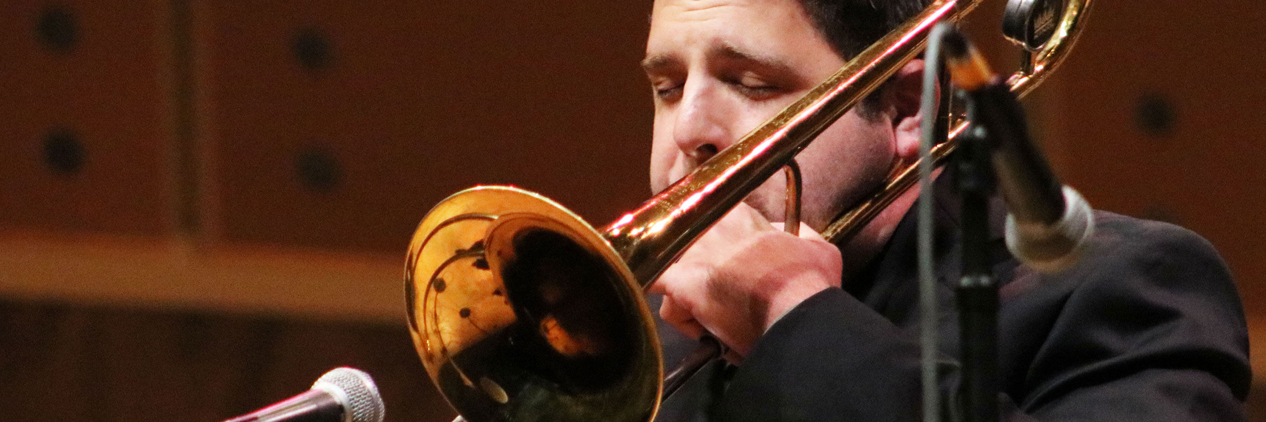 A trombonist plays into a microphone.