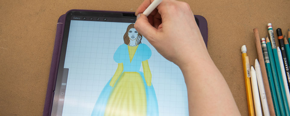 Graduate costume designer sketches a costume on her tablet.