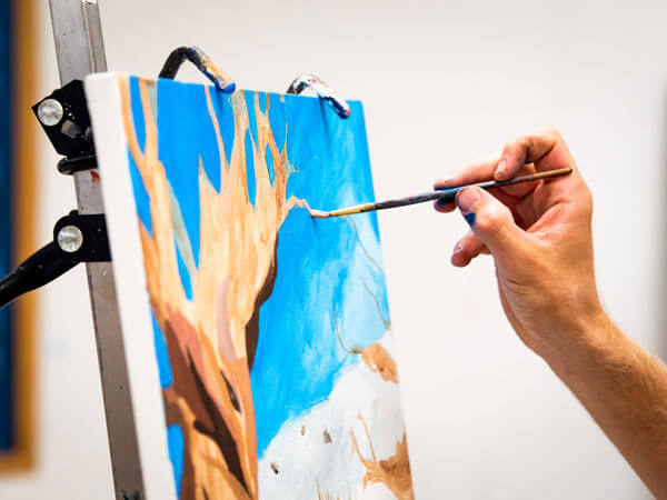 Student paints on a canvas.