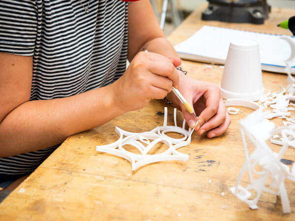 A student builds a sculpture with plastic in a 3D fundamentals class.