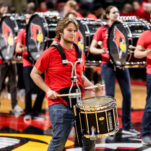The Basketball drumline performs on the court.