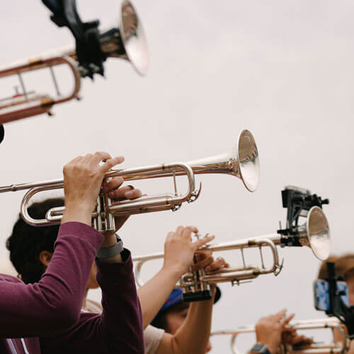The trumpet players of a marching band raise their instruments.