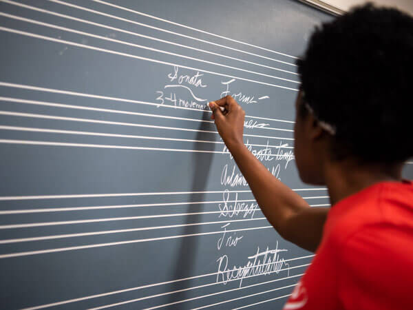 Students writes on a chalkboard.