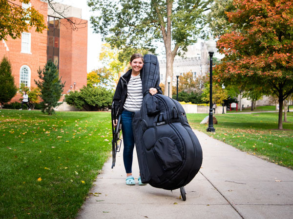Student rolls her double bass case to class.