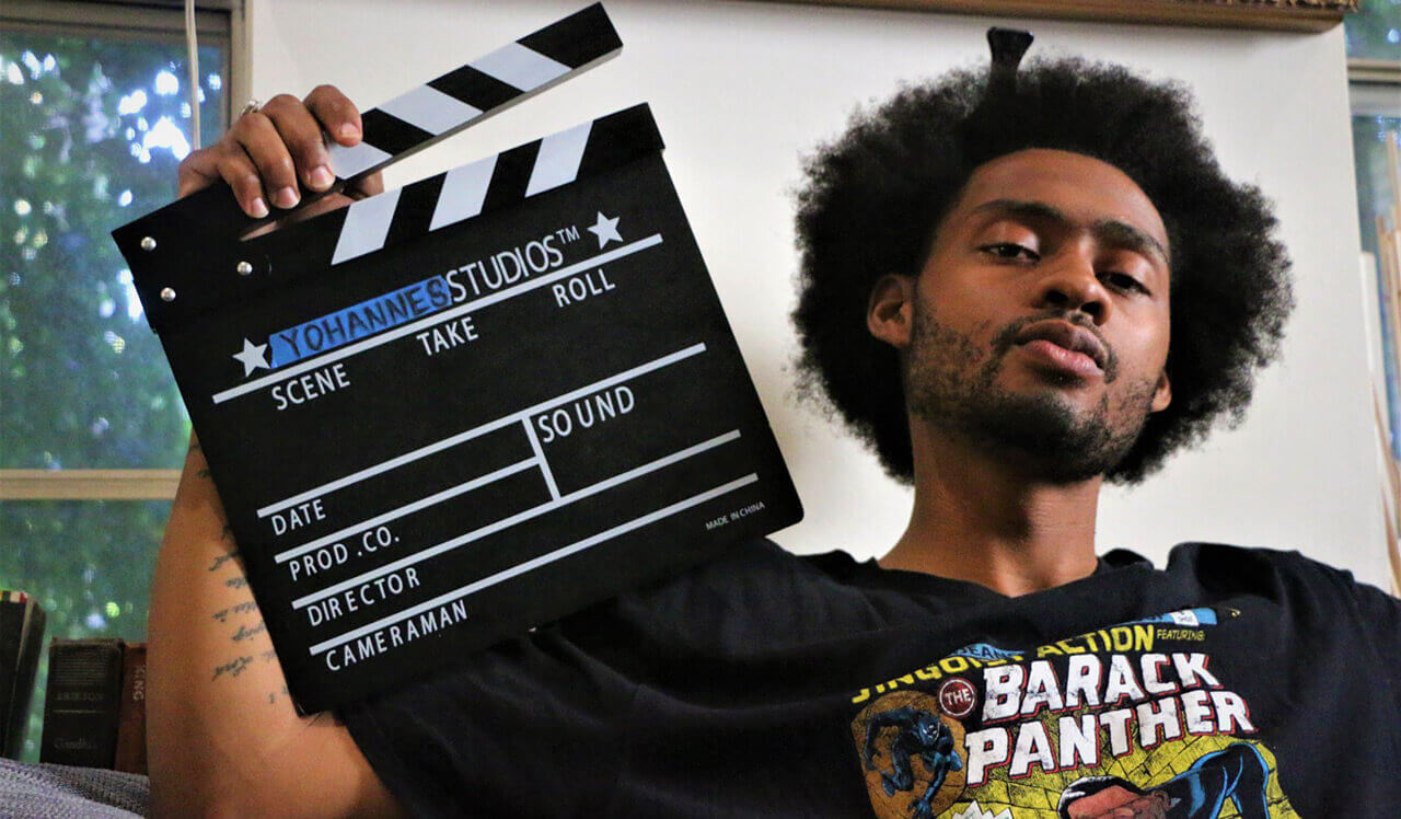 Yohannes Yamassee holding a clapperboard.